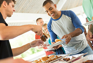 A man serves another man some barbecue meat