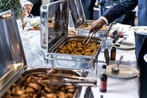 Catered trays with a business professional selecting food. 