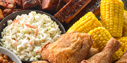 Iris' Down Home Fried Chicken Feast with a ramekin of coleslaw, corn on the cob, ribs, chicken and baked bean
